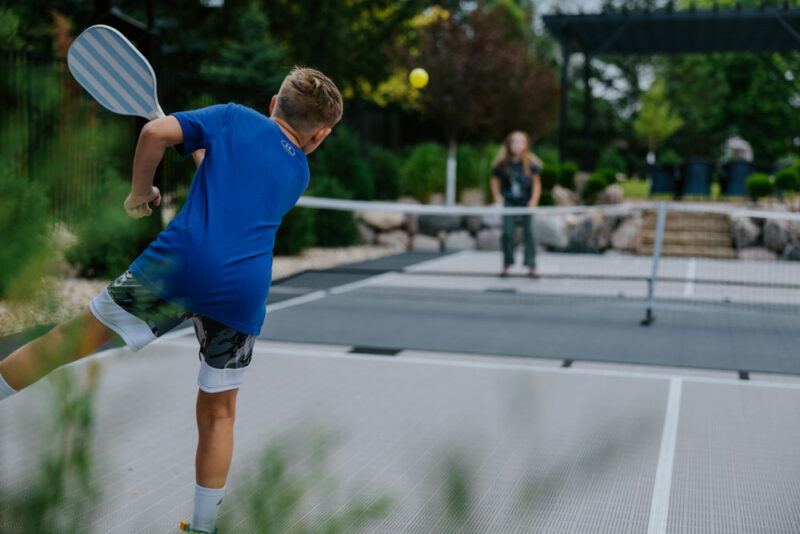 children play pickleball in their backyard court