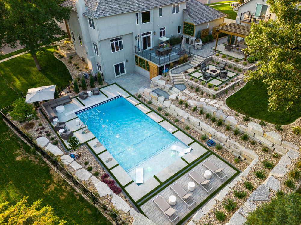 a sioux falls residential backyard with multi-level retaining walls, a pool, patio, and more