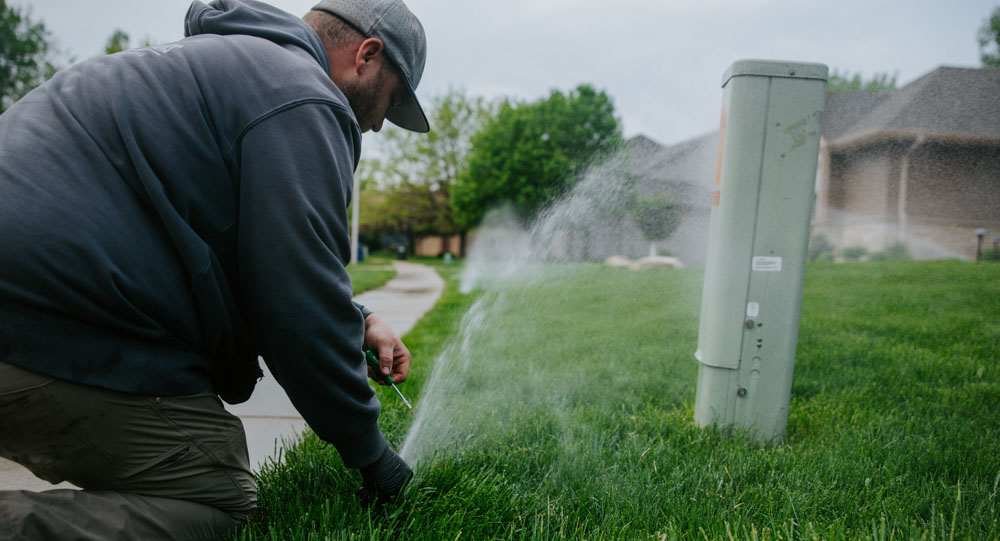 Weller Brothers Landscape Professionals employee adjusts a sprinkler head