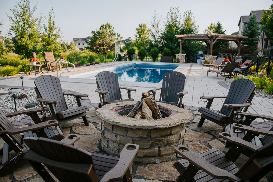 Natural stone fire pit with seating near in-ground pool in Sioux Falls, SD.