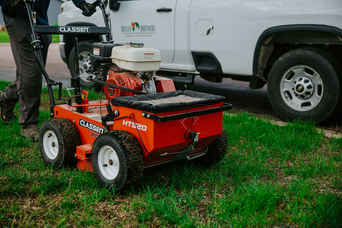 Weller Brothers lawn care professional overseeding a lawn in Sioux Falls, SD near the street.