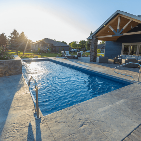 outdoor pool surrounded by a concrete and paver patio