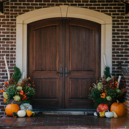 front door of a home with fall mums and pumpkins