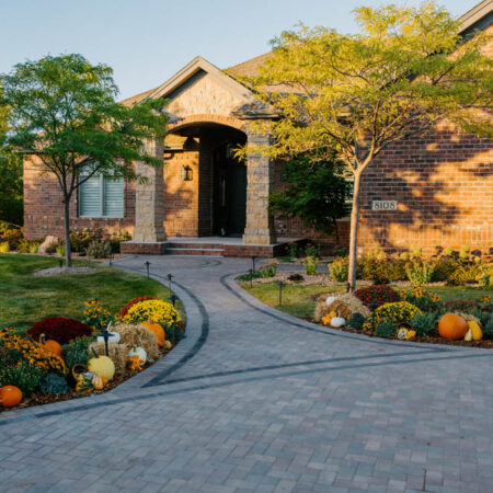 brick home with paver driveway and fall mums