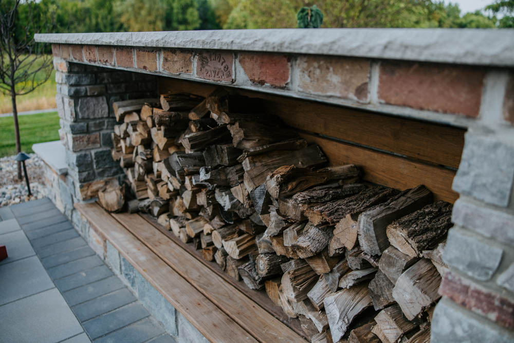 a closeup of custom firewood storage in a backyard