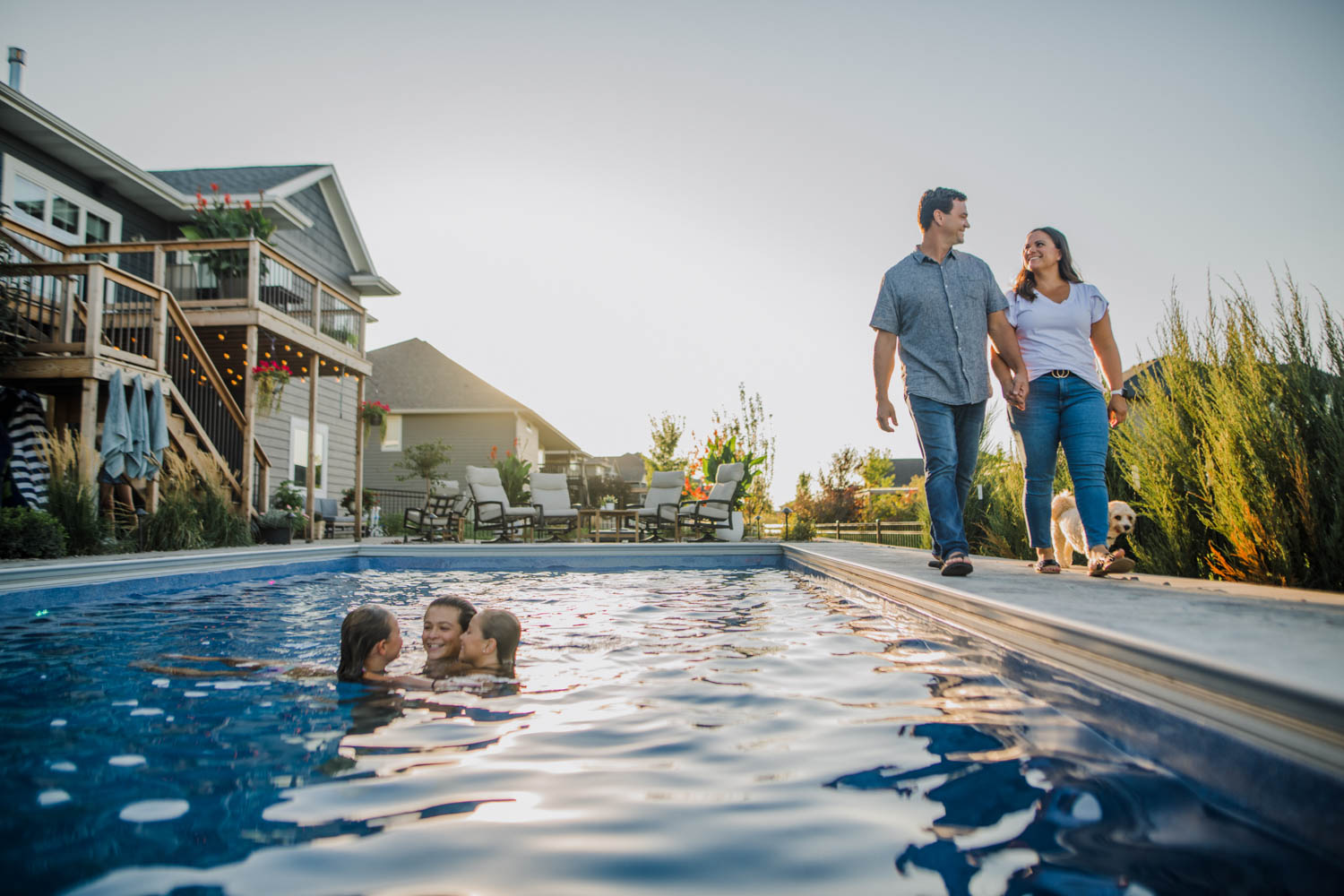 A couple and their children enjoy their backyard patio and pool